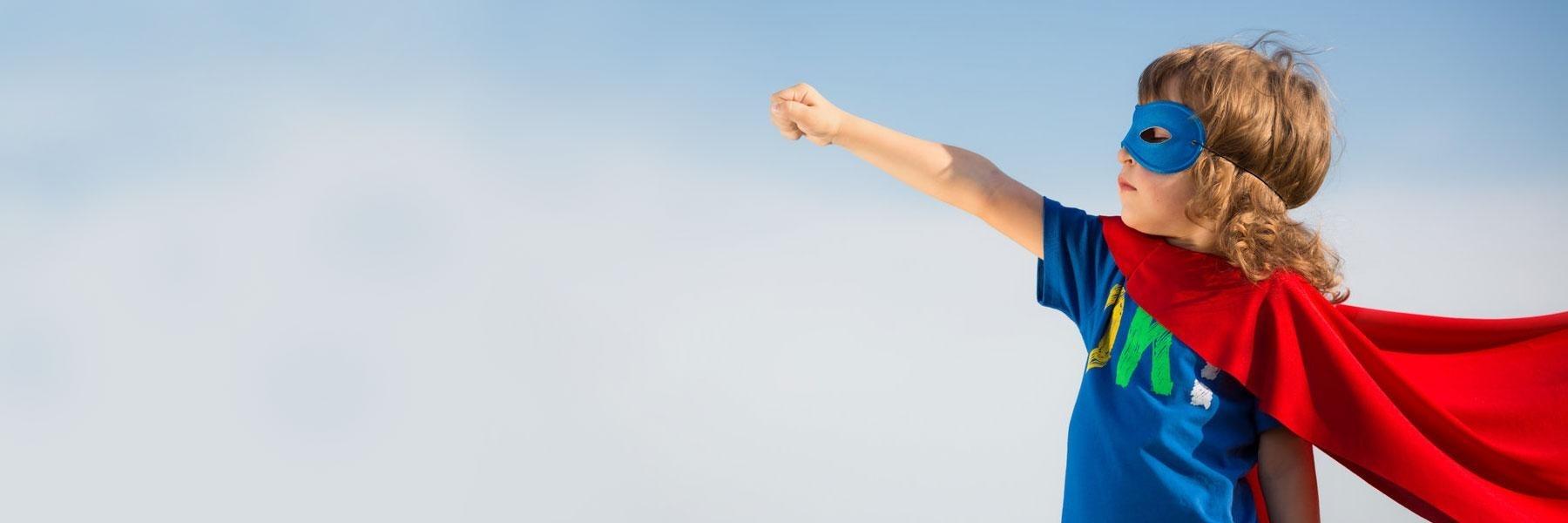 Child wearing a superman cape outside